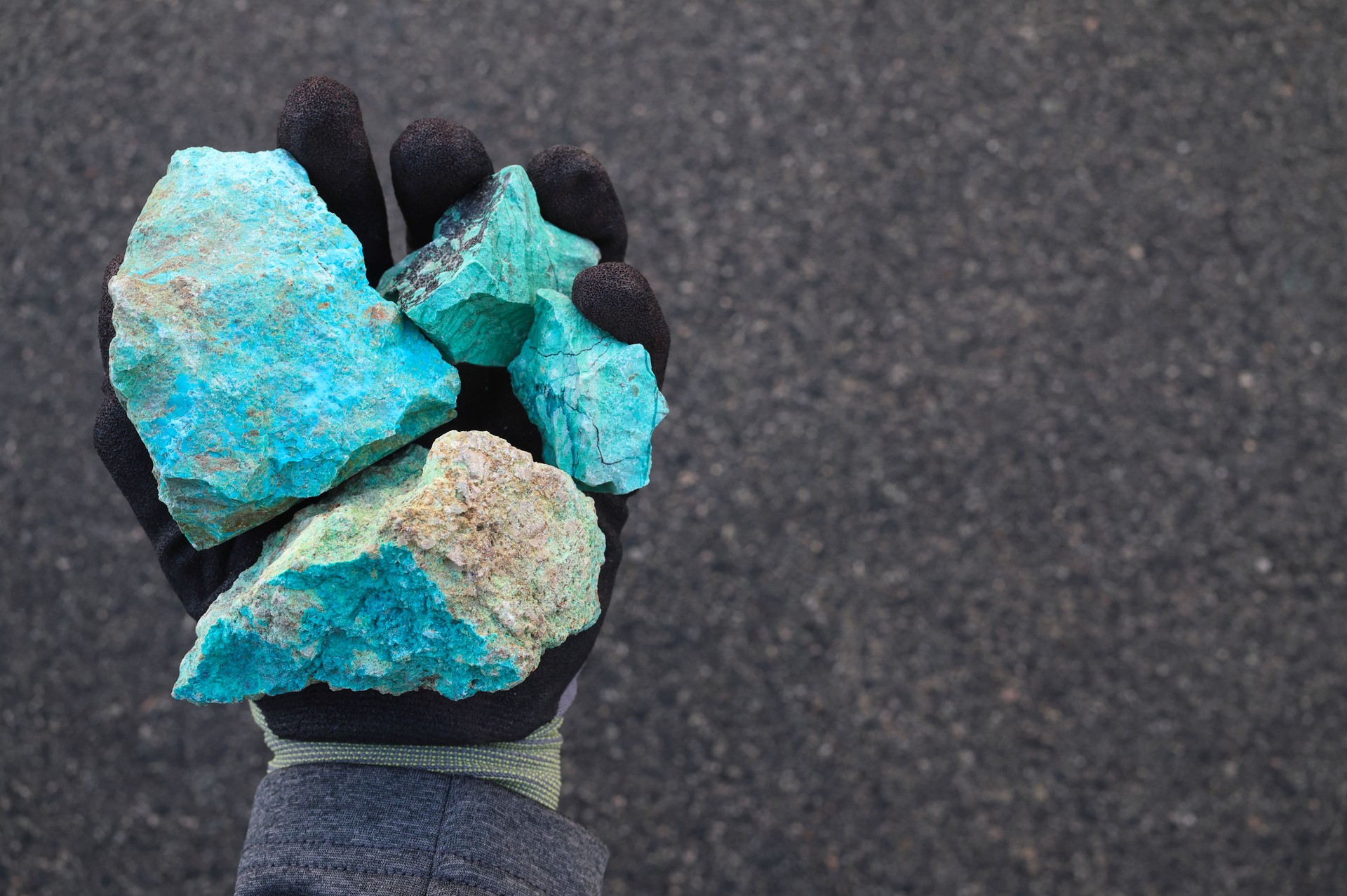 Blue green copper (Cu) oxide ore, held in hand with protective glove. Mining.